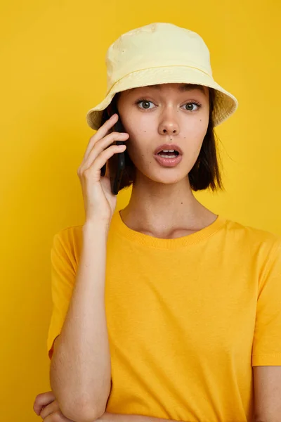 Photo pretty girl yellow t-shirt and Hat summer style with phone Lifestyle unaltered — Φωτογραφία Αρχείου