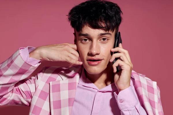 Chico guapo con un teléfono en la mano chaqueta rosa moda estilo elegante estilo de vida inalterado — Foto de Stock