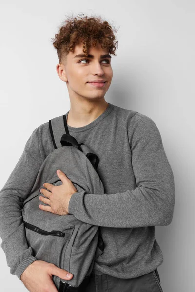 Handsome young man in a gray sweater backpack fashion isolated background — Stockfoto