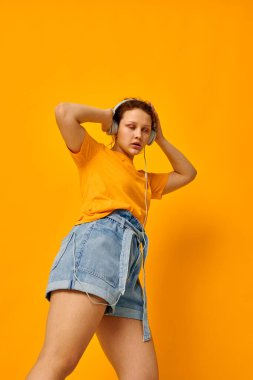 Komik kız kulaklıkla müzik dinliyor. Gençlik tarzı sarı arka plan değiştirilmemiş.