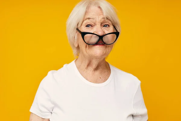 Портрет старої дружньої жінки в білій футболці носить окуляри ізольований фон — стокове фото