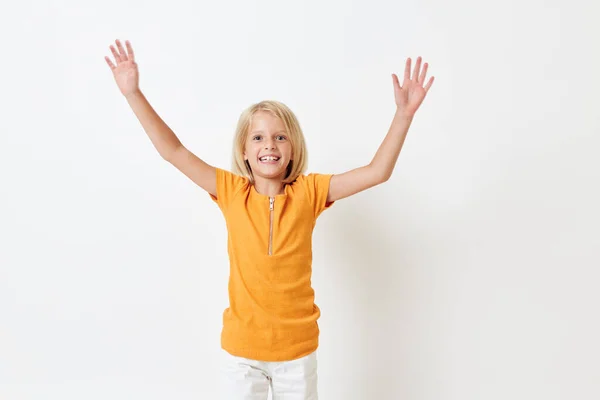 Klein meisje met blond haar in een geel t-shirt geïsoleerde achtergrond — Stockfoto