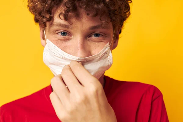 Retrato de um jovem encaracolado vestindo uma t-shirt vermelha máscara médica no rosto posando tiro monocromático — Fotografia de Stock