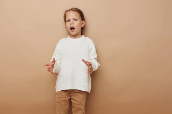 하얀 스웨터를 입고 행복하게 웃고 있는 어린 소녀의 모습은 손을 흔들며 몸짓을 하는 모습을 배경으로 한다 — 스톡 사진