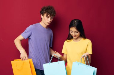 Genç erkek ve kız alışveriş torbaları el ele tutuşturulmuş, değiştirilmemiş arka plan