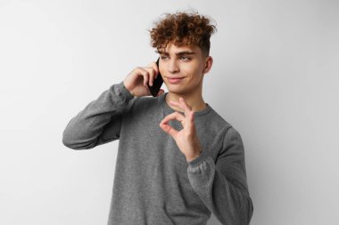 Yakışıklı genç adam telefonda konuşuyor. Duygularını dışa vuruyor.