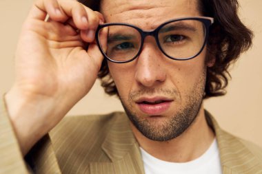 Takım elbiseli yakışıklı bir adam. Duygularını belli eden gözlük takıyor.