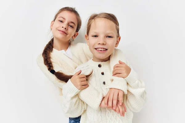 Дві маленькі дівчата обіймають світлий фон подруги — стокове фото