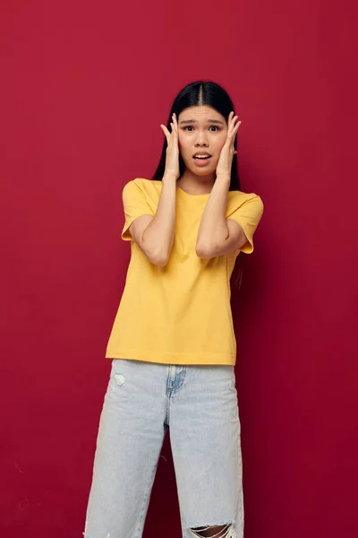 Encantadora jovem mulher asiática em uma camiseta amarela gesticulando com as mãos divertidas modelo de estúdio inalterado — Fotografia de Stock