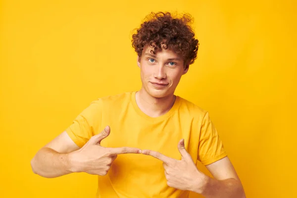 Portrét mladého kudrnatého muže na sobě stylové žluté tričko pózující žluté pozadí beze změny — Stock fotografie