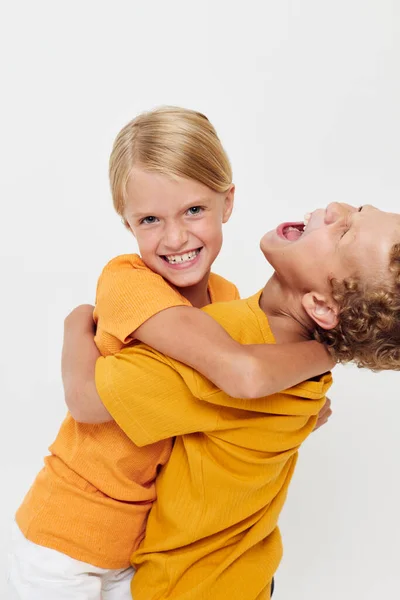Imagen de niño y niña positivos en camisetas amarillas de pie lado a lado emociones de la infancia inalteradas — Foto de Stock