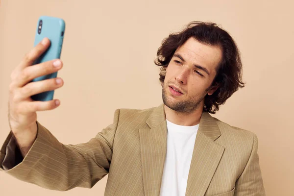 Привабливий чоловік в костюмі позує емоції, дивлячись на телефон ізольований фон — стокове фото