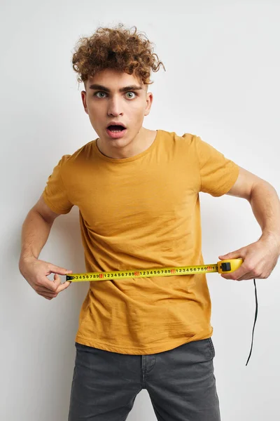 Sapık adam mezuranın ölçüsünü sarı tişörtle ölçüyor. — Stok fotoğraf
