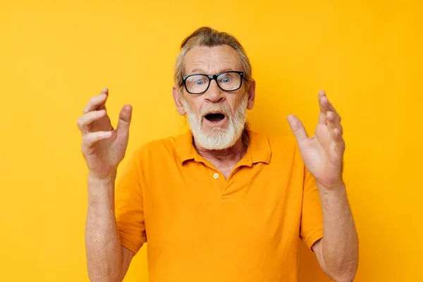 Senior grey-haired man wearing glasses yellow shirt posing isolated background — ストック写真