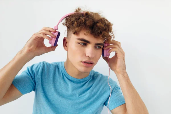 Bonito jovem homem em azul t-shirts rosa fones de ouvido moda isolado fundo — Fotografia de Stock