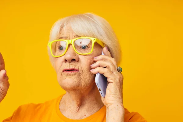 Портрет старой дружелюбной женщины весело говорить по телефону желтый фон — стоковое фото