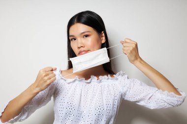 Çekici Asyalı genç kadın tıbbi maske koruması. Geçmişi değiştirilmemiş.