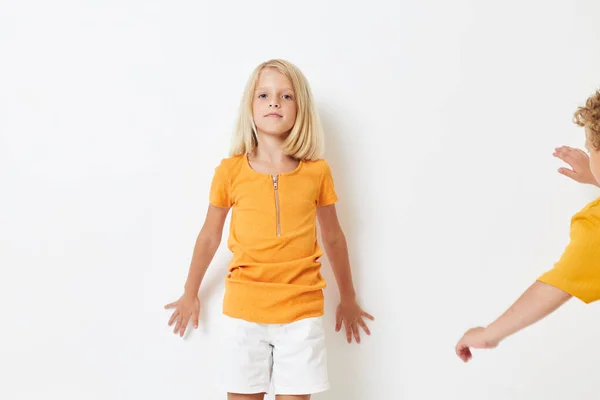 Ein Junge und ein Mädchen in gelben T-Shirts stehen nebeneinander auf hellem Hintergrund und posieren — Stockfoto