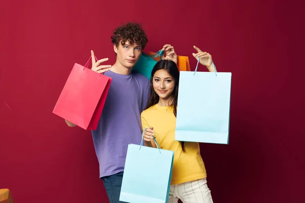 Teenagers in colorful T-shirts with bags Shopping red background unaltered — Stock Photo, Image