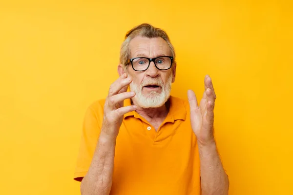 Portrait of happy senior man wearing glasses yellow shirt posing unaltered — Foto de Stock