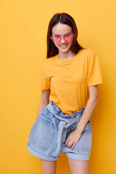 Photo pretty girl fashion in yellow t-shirt denim shorts isolated background — Stock Photo, Image