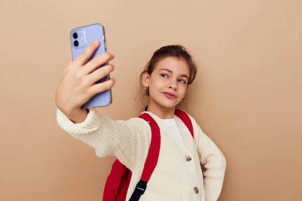 Bella ragazza che parla al telefono con uno zaino sfondo beige — Foto Stock