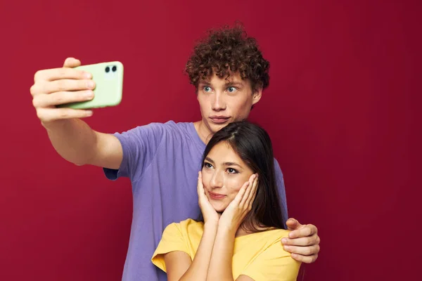 Una pareja joven en camisetas coloridas con un teléfono Estilo juvenil — Foto de Stock