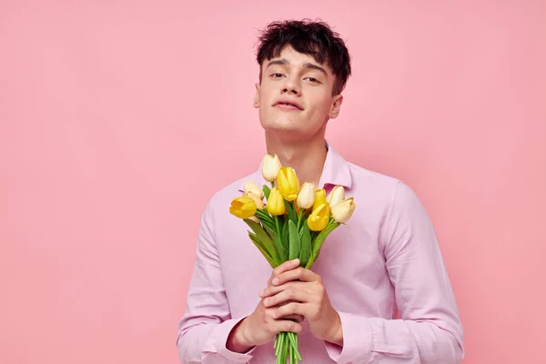 Красивий чоловік в рожевій сорочці з букетом квітів жестикулює своїми руками модель студії — стокове фото