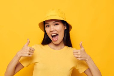 Sarı tişörtlü güzel esmer ve şapkalı. Duygularını ortaya koyan sarı arka planda değişiklik yok.