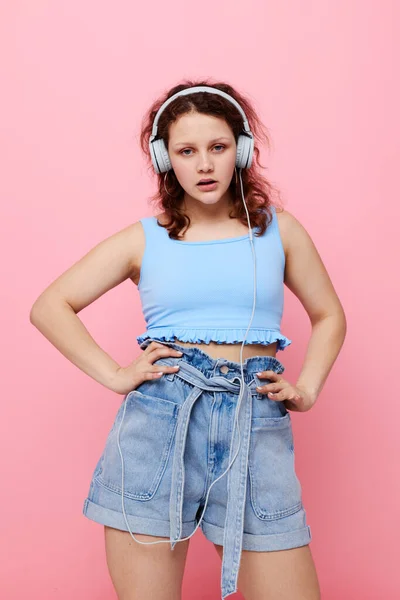 Портрет молодой девушки в наушниках, слушающей музыку на розовом фоне без изменений — стоковое фото