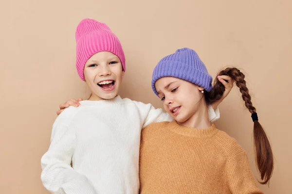 Twee grappige meisjes knuffelen poseren kleurrijke hoeden — Stockfoto
