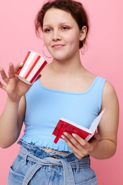 Neşeli kadın elinde bir defter tutuyor. Tek kullanımlık cam. Pembe arka plan değiştirilmemiş.