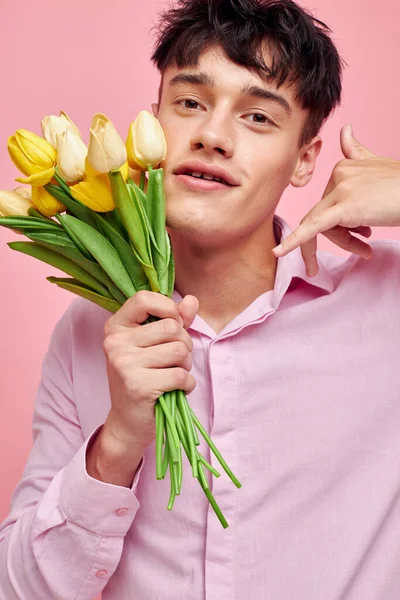Портрет молодого чоловіка в рожевій сорочці з букетом квітів, що жестикулює руками Стиль життя незмінний — стокове фото