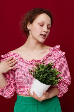 Ayakta duran ve saksıda çiçekleri tutan genç bir kadın.