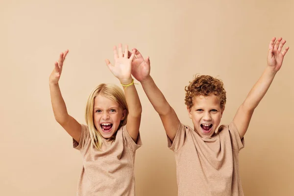 Мальчик и девочка в бежевых футболках позируют для веселого детства без изменений — стоковое фото