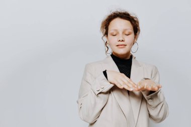 Takım elbiseli neşeli bir kadın elleri ve duyguları ile sarı arka planı değişmeden hareket eder.