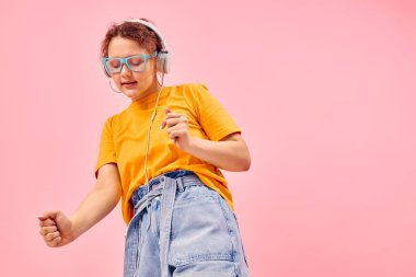 Güzel bir kadın mavi gözlük takıp kulaklıkla müzik dinliyor. Arka planda bir değişiklik yok.