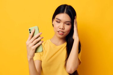 Akıllı telefonlu güzel bir Asyalı kadın portresi. Eğlenceli duygular, yakın çekim yaşam tarzı değiştirilmemiş.