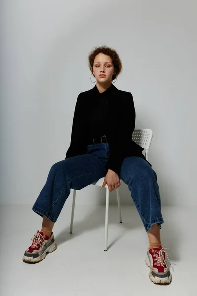 Портрет молодої жінки, що сидить на стільці в чорній куртці мода позує ізольовані фони незмінними — стокове фото