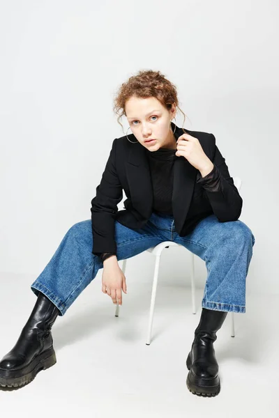 Красивая женщина сидит на стуле в черной куртке моды позируя образ жизни неизменным — стоковое фото