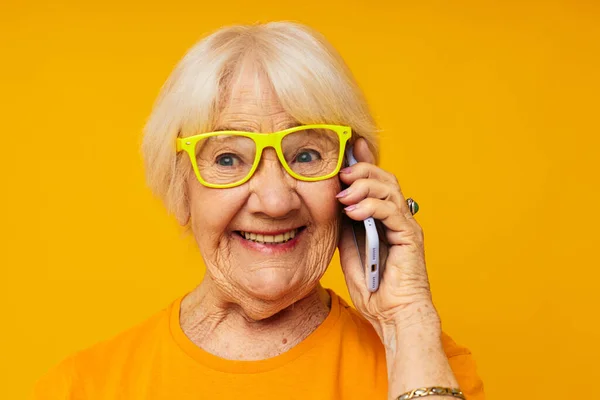 Фото пожилой женщины на пенсии счастливый образ жизни в желтых футболках с изолированным фоном телефона — стоковое фото