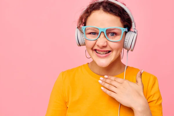 Fröhliche Frau mit blauer Brille, die Musik über Kopfhörer hört isolierte Hintergründe unverändert — Stockfoto