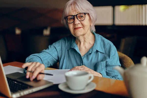 Feliz mujer mayor sentada en un café con una taza de café y un portátil Estilo de vida inalterado — Foto de Stock