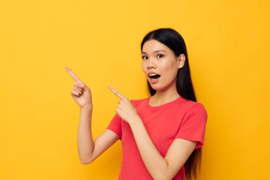 Çekici genç Asyalı kadın kırmızı tişörtleri modern stil stüdyo modelini değiştirmeden poz veriyor.