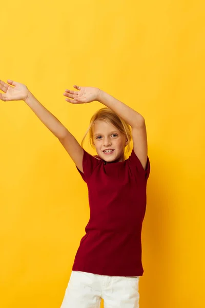 Vrolijk meisje met blond haar gebaren met haar handen geel achtergrond — Stockfoto