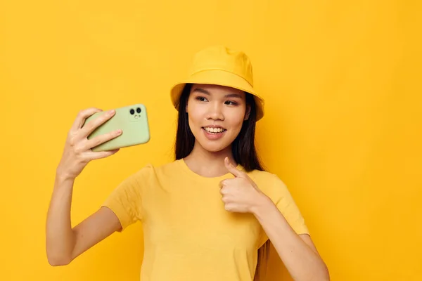 노란 모자와 티셔츠를 입은 아시아인의 아름다운 여성 이 아무런 변화 없이 전화로 이야기하는 모습 — 스톡 사진