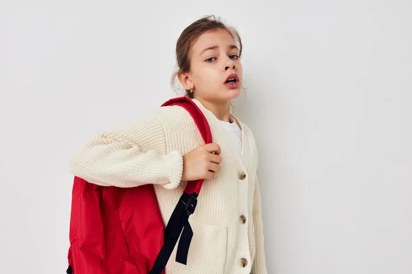 Roztomilý dívka ruka gesto červená batoh světlo pozadí — Stock fotografie