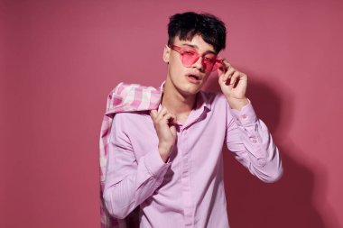 Kendine güveni olan genç bir adam pembe ekose ceket modasında pembe arka plan değiştirilmeden poz veriyor.