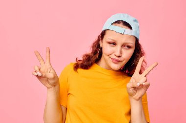 Sarı tişörtlü ve mavi şapkalı neşeli kadın duygularını belli ediyor.