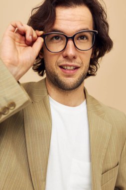 Gözlüklü çekici bir adam. Duyguları olan, elleri bej arkaplan şeklinde hareket eden.